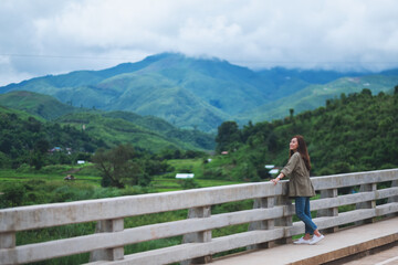 A beautiful young asian woman standing on the bridge and looking at mountains and nature view