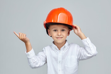 little boy in a construction helmet. the finger points in the direction of empty space.