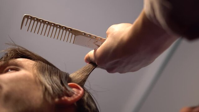 barber hands holds scissors and comb performing haircut