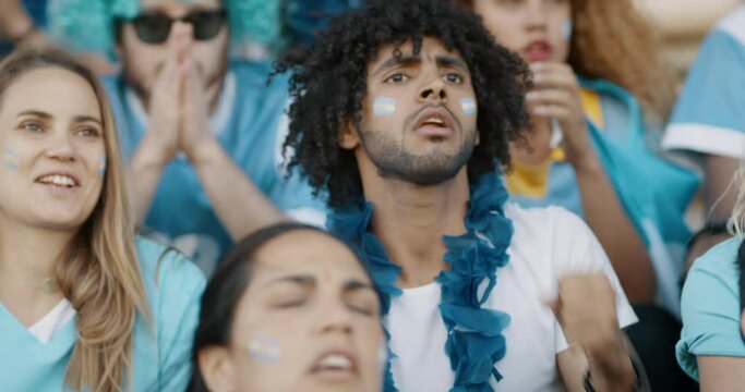 Argentinian soccer fans watching the match live from the stadium and starts celebrating after their team scoring a goal. Spectator at stadium cheering when their national team scores a goal.
