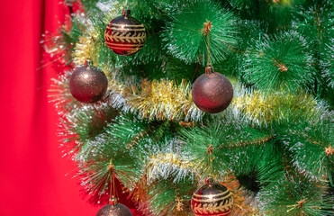 Christmas background: many brown and gold Christmas balls weighs on a branch of a Christmas tree against a red background. Place for text.