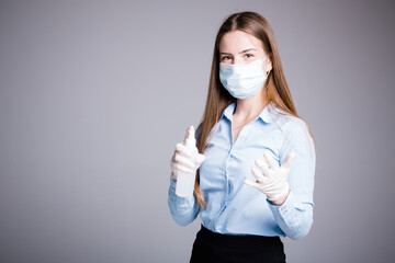 Portrait of an office worker girl in a medical mask and gloves who holds an antiseptic and sprinkles it on her hands for disinfection