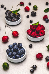 Assorted berries in bowls: bilberry, blueberry, currant, blackberry, cherry and raspberry