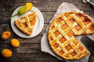 Summer apricot or peach pie homemade on wooden background, top view. Delicious fruit dessert. Fruit cake. Copy space.