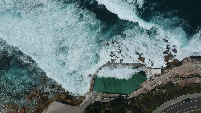 Bronte Rock Pool also known as Bronte Baths in Sydney being hit by big waves, the aerial shot is steady at the beginning and tracks slowly towards the end of the clip