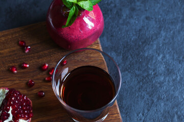 Pomegranate juice with pomegranate on a wooden board on a dark background. Natural drink.