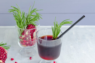 Pomegranate non-alcoholic cocktail with rosemary on a light background. Fruit grains in a glass. Natural healthy drink