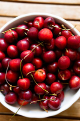 Bowl with tasty cherries on wooden table