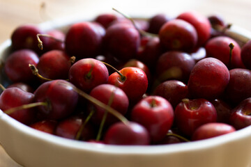 Bowl with tasty cherries on wooden table
