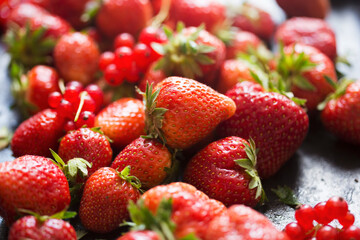 Strawberries and red currants on black background 