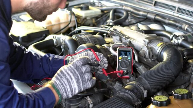 Auto mechanic checking suspension of a lifted car. Experience car service technician working at the garage. Mechanic repairing car at workshop.