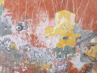Damaged wall texture. Yellow , red, pink and gray paint peeling off the wall.