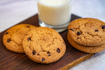 Delicious homemade oatmeal cookies and a glass of milk on a wooden board. Tasty breakfast.