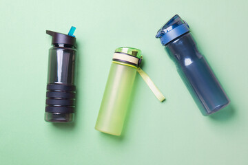 black, green and blue sport plastic bottles lying on green colored paper background