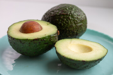 whole and sliced avocado on a blue plate
