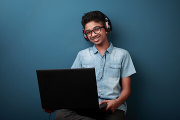 Happy young boy wearing headset smiles while learning through laptop