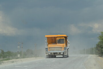 Big yellow truck  driving on dusty road