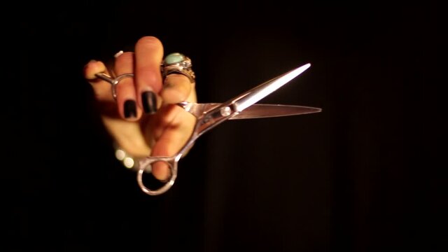 Professional woman hairdresser barber hand moving scissors shears cutting movement in air on black background