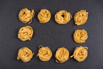 Fettuccine or Tagliatelle on gray background. Pasta background. Spaghetti nests