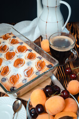 cottage cheese apricot casserole decorated with icing sugar, slices of berries on a background of a white coffee pot on a wooden table