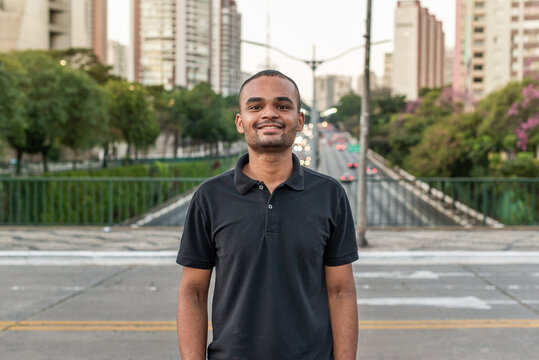 Jovem negro parado sorrindo na rua em S&atilde;o Paulo, Brasil