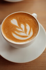 Breakfast in the cafe. Beautiful white mug with cappuccino or latte coffee on a wooden table. View from above. 
