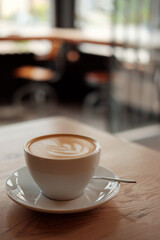 Breakfast in the cafe. Beautiful white mug with cappuccino or latte coffee on a wooden table. View from above. 