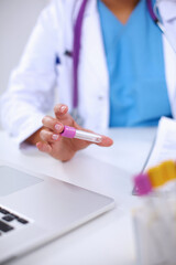 Woman researcher is surrounded by medical vials and flasks, iso