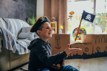 The little boy imagining the pirate excitedly throws and bites the gold coins