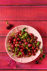 Flat lay of a big plate full of fresh and ripe cherries