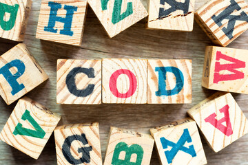 Alphabet letter block in word COD (Abbreviation of cash on delivery) with another on wood background
