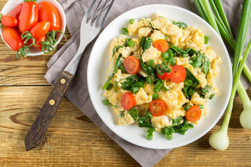 scrambled eggs with spinach and tomatoes on a white plate.