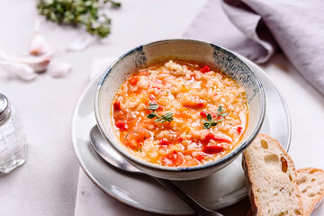 Vegetarian spicy tomato rice soup on grey concrete background. Selective focus
