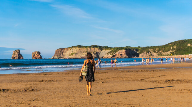 Hendaye, Lapurdi / France &raquo;; July 5, 2020: A young woman strolling along the beach in Hendaye, French Basque country