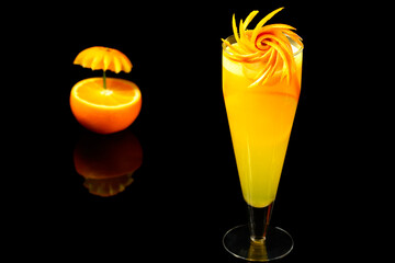 orange drik with heart made in an orange next to the cup photographed in black background