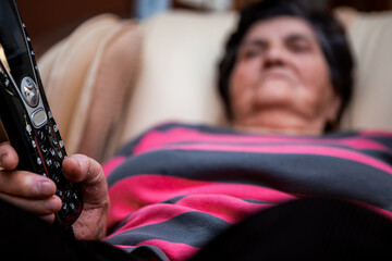 Selective focus on the remote control from the massage chair in the hand of a senior woman. A...