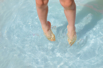 close-up - feet of a five-year-old boy who jumps, plays in the water in a children's inflatable pool, splashes water