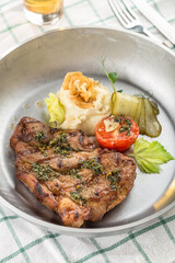 Grilled pork steak with mashed potato, pickles and glass of beer on the table