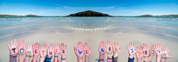 Children Hands Building Colorful Word Together We Are Strong. Ocean And Beach As Background