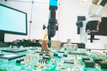 Miniature repair man on mainboard, Miniature figure of worker team try to repair cpu on mainboard.