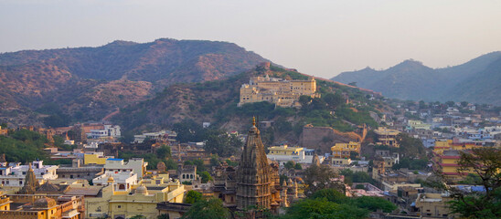 View over Hindu temple pagoda and city of Amber onto hills and mountain scenery and landscape in...