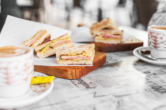 Traditional Portuguese breakfast from Madeira - a cup of coffee with milk and cheese and ham sandwich with local bread 'bolo do caco'