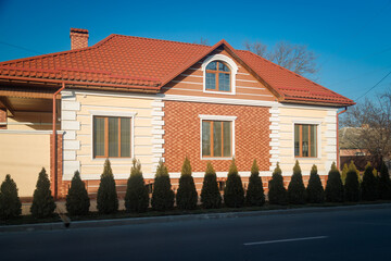 House facade with evergreen bushes in front of it, blue sky background