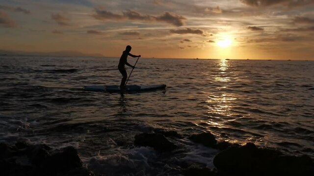 Young boy doing paddle surf at sunset
