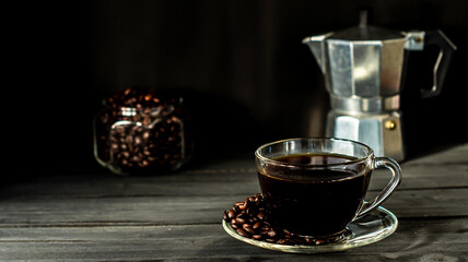 Hot coffee in a coffee cup and roasted coffee beans with a dark tone wood floor. And there is a copy space.