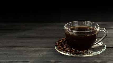 Hot coffee in a coffee cup and roasted coffee beans with a dark tone wood floor. And there is a copy space.