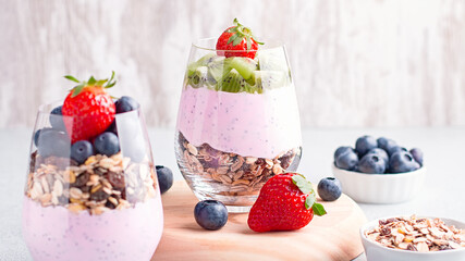 Superfoods layered pudding with granola, blueberry and strawberry in glasses. Yogurt with chia seeds, berries, kiwi and muesli for healthy breakfast, copy space. Perfect for summer snack or dessert