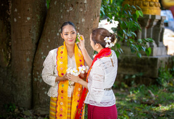Portrait of two Asian women or Myanmar women doing make up on each other while standing at outdoor in Temple.