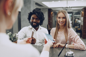 Business trip concept. Black man and caucasian woman businesspeople colleagues checking-in in hotel