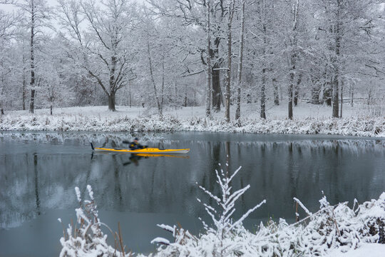 Man paddling in yellow kayak in river in winter